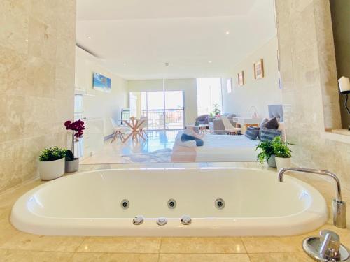 a large white bath tub in a living room at 237 Santai - Second floor studio by uHoliday in Casuarina