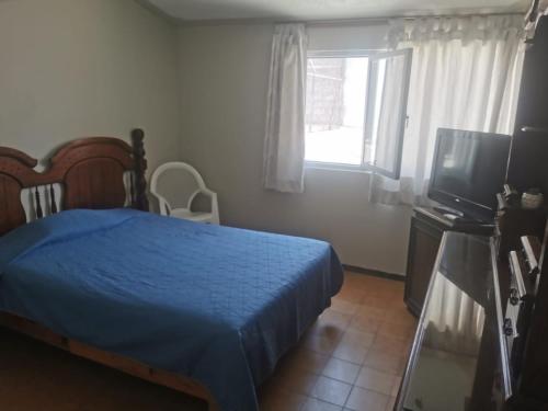 a bedroom with a blue bed and a television at Margaritas Eco Haus in Querétaro