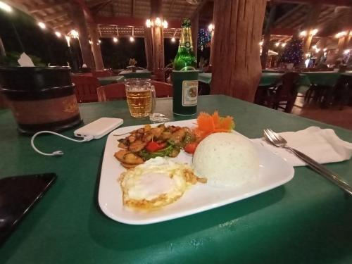 a plate of food on a table with a bottle of beer at Happy Lagoon Bungalow in Khao Lak