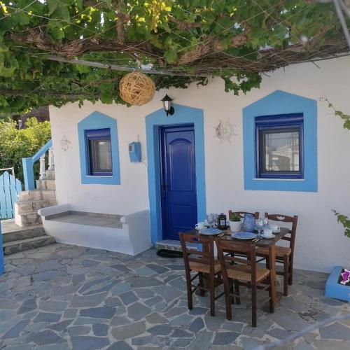 einen Tisch und Stühle vor einem Haus mit blauer Tür in der Unterkunft Sea Breeze in Archangelos