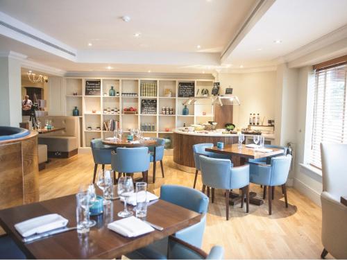 a restaurant with wooden tables and blue chairs at Cottons Hotel and Spa in Knutsford