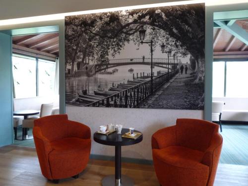 a dining room with two chairs and a painting on the wall at The Originals City, Hôtel Rey du Mont Sion, Saint-Julien-en-Genevois Sud in Saint-Blaise