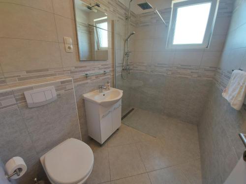 y baño con aseo, lavabo y ducha. en Apartments Marija en Draga Bašćanska