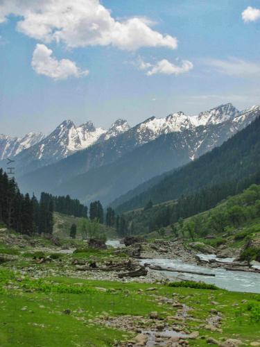 a valley with a river and mountains in the background at Kashmir Outlook Adventures in Pahalgām