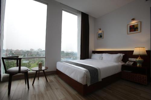 a hotel room with a bed and a table and window at Empyrean Dhaka City Centre in Dhaka