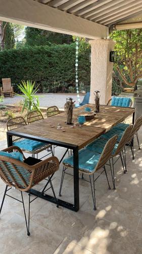 einen Holztisch und Stühle auf einer Terrasse in der Unterkunft Villa Petit Paradis - Gigaro in La Croix-Valmer