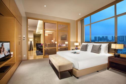 a bedroom with a large white bed and a television at Somerset Grand Central Dalian in Dalian