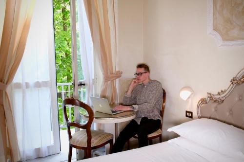 a man sitting at a table with a laptop at Hotel Tahiti in Viareggio