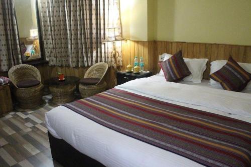 um quarto de hotel com uma cama grande e cadeiras em Hotel Miknaon Inn em Rishop