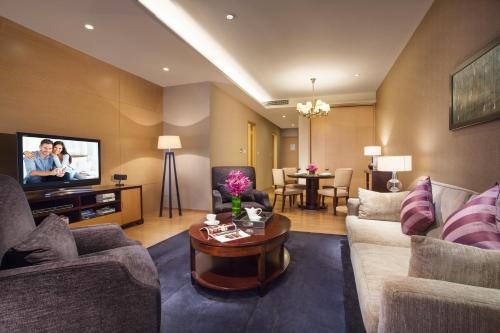 a living room with a couch and a tv at Somerset Grand Central Dalian in Dalian