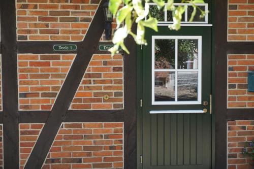 a brick house with a green door and a window at Beekenhof in Bommelsen