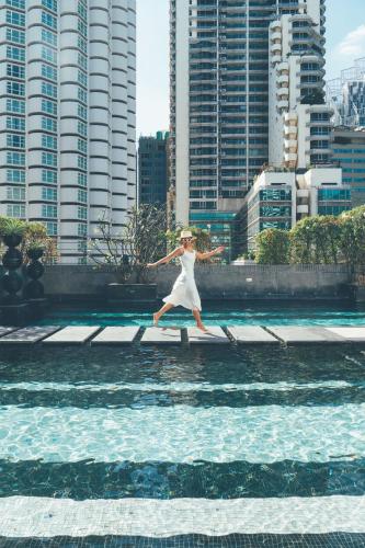 a woman jumping into a pool of water at Mövenpick Hotel Sukhumvit 15 Bangkok in Bangkok