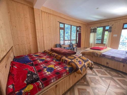 two beds in a room with wooden walls and windows at Shiva mountain guest house & Cafe in Tosh