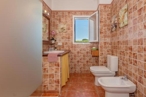 a bathroom with two toilets and a sink and a window at Racó Blau in Cap d'en Font