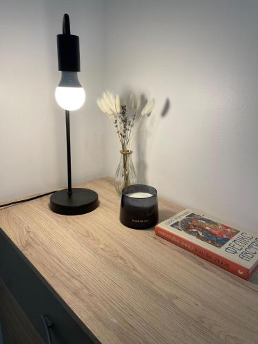 un tavolo con una lampada, un libro e un vaso di fiori di Logement entier : Studio neuf avec jardin a Vallauris