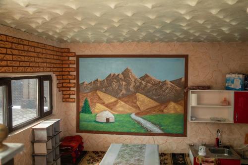 a painting of mountains on the wall of a kitchen at Гостевой дом Датка in Talas