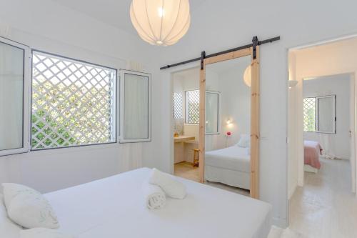 a white bedroom with a bed and a window at Villa Juanes in Ciutadella