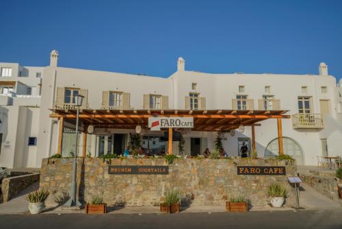 a large white building with a restaurant on the street at Faro Sunset Suites in Mikonos