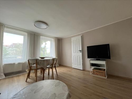 een woonkamer met een tafel en een flatscreen-tv bij Brezno Apartament in Gdańsk