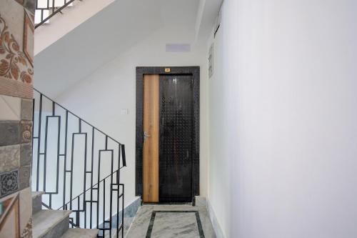 a black door in a white hallway with stairs at FabExpress Amar Raj Villa - Nr Eco Park in Kolkata
