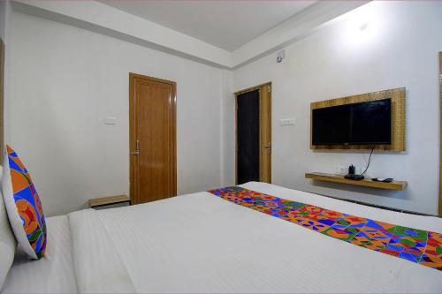 a bedroom with a white bed and a flat screen tv at FabExpress Amar Raj Villa - Nr Eco Park in Kolkata
