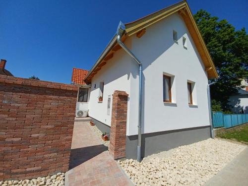 a white house with a red brick wall at Fazekas Vendégház in Balatonkeresztúr