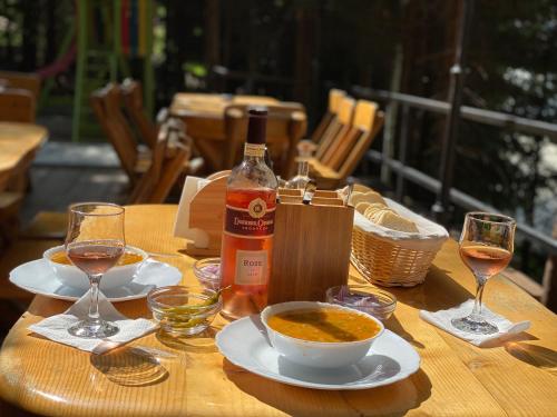 a table with a bottle of wine and a bowl of soup at Altitude Guest House Ranca in Ranca