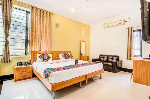 een slaapkamer met een groot bed en een stoel bij FabHotel Emara Grand in Bangalore