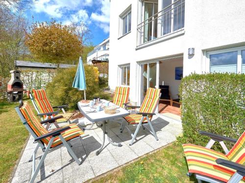 une terrasse avec des chaises et une table avec un parasol dans l'établissement Haus Strandjuwel - Haus 2 "Sonnenträumer" mit Sauna, Kamin, Terrasse, à Sellin