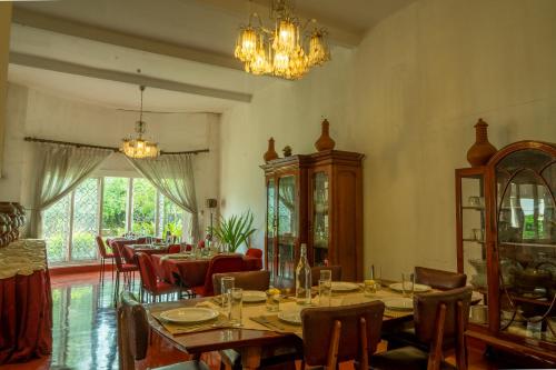 una sala da pranzo con tavoli, sedie e lampadario a braccio di Fortuna Heritage Home a Kandy