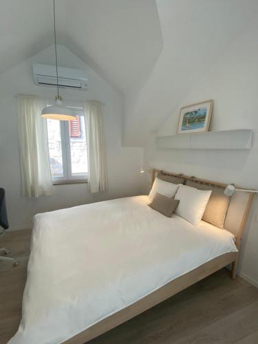 1 dormitorio con 1 cama blanca grande y 2 almohadas en Blu Riva Hvar, en Hvar