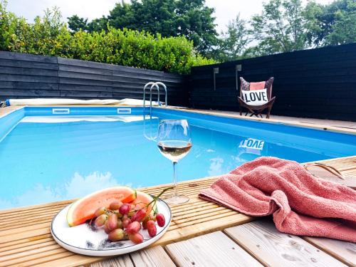 a glass of wine and a plate of fruit next to a swimming pool at Luxe vakantiehuis Nova met zwembad in Ouddorp