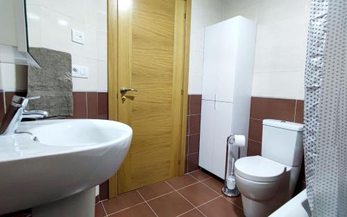 uma casa de banho com um lavatório branco e um WC. em Os Reloxos II em Mondariz-Balneario