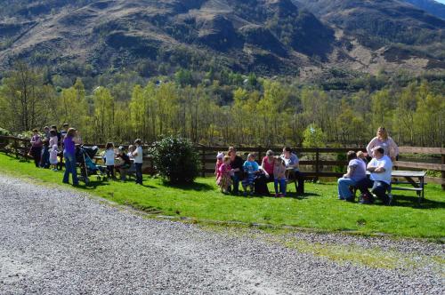 a group of people sitting on benches next to a fence at MacDonald Hotel & Cabins in Kinlochleven