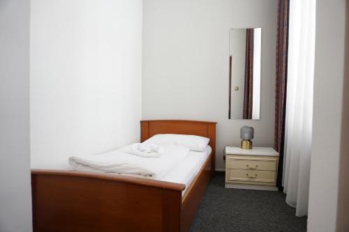 a small bedroom with a bed and a mirror at Hotel Pension Lumes - Self Check In in Vienna