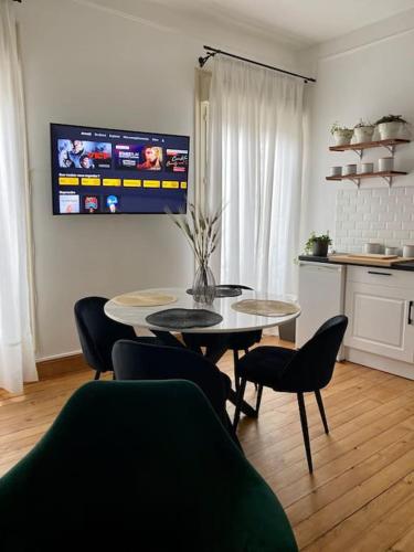 - un salon avec une table, des chaises et une télévision dans l'établissement Appartement VH III, au Mans