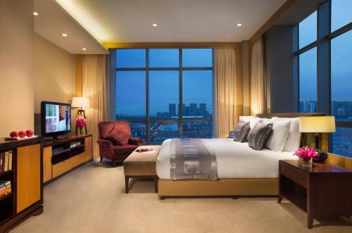 a hotel room with a large bed and a television at Somerset Grand Central Dalian in Dalian
