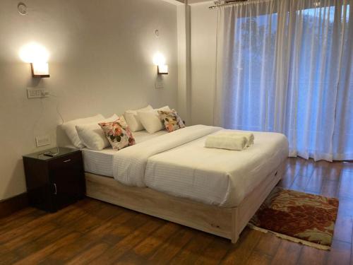 1 dormitorio con 1 cama grande con sábanas y almohadas blancas en Miknaon Farm Stay, en Pedong