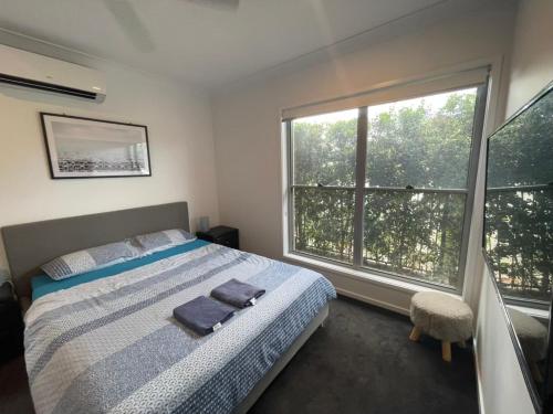 a bedroom with a bed and a large window at Tropical Ocean Vibe Holiday House in Strathpine in Strathpine