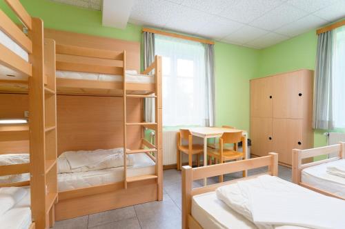 a dorm room with bunk beds and a table at Radfahrerherberge Krems in Krems an der Donau