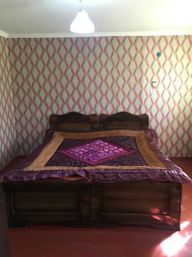 a bed in a room with a purple comforter at MACHABELl in Ambrolauri