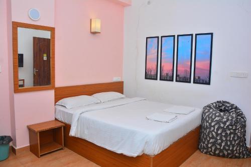 een slaapkamer met een wit bed en een spiegel bij FabExpress GL Classic With Bar, Porvorim in Oud Goa