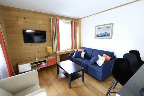 ein Wohnzimmer mit einem blauen Sofa und einem TV in der Unterkunft Le Schuss Tignes, appartement cosy 4 personnes in Tignes