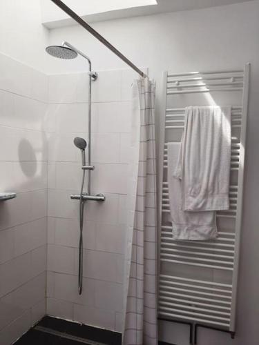 La salle de bains est pourvue d'une douche et d'une serviette blanche. dans l'établissement St Elme, maison de pêcheurs, WIFI jardin, à Ault