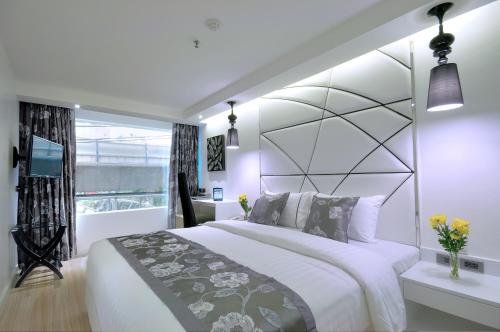 a white bedroom with a large bed and a window at Sukhumvit Suites Hotel in Bangkok