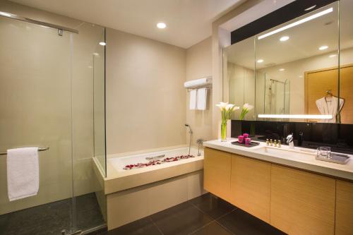 a bathroom with a shower and a sink and a mirror at Somerset Grand Central Dalian in Dalian