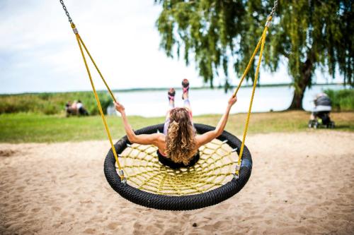 a woman sitting on a tire swing on the beach at traumHaff Historischer Kahnschifferhof mit Kamin, liebevoll restauriert in Vogelsang