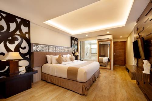 a bedroom with a large bed and a television at Villa Kayu Raja in Seminyak