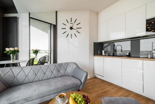 a living room with a couch and a clock on the wall at Q18 ApartHotel in Bydgoszcz