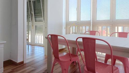 una mesa de comedor con 4 sillas rojas en una habitación con ventanas en Acacias IV, en Benidorm